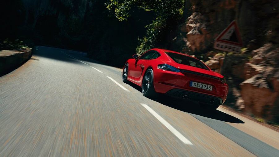 A red Porsche 718 Cayman GTS drives around a mountain road.