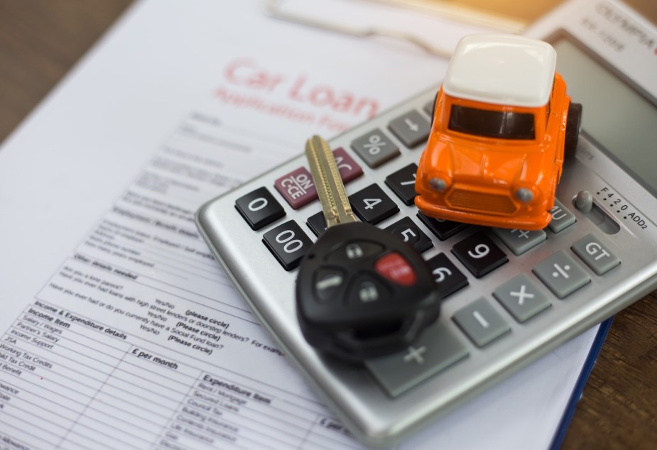 Toy car, car keys, and calculator stacked on a car loan document