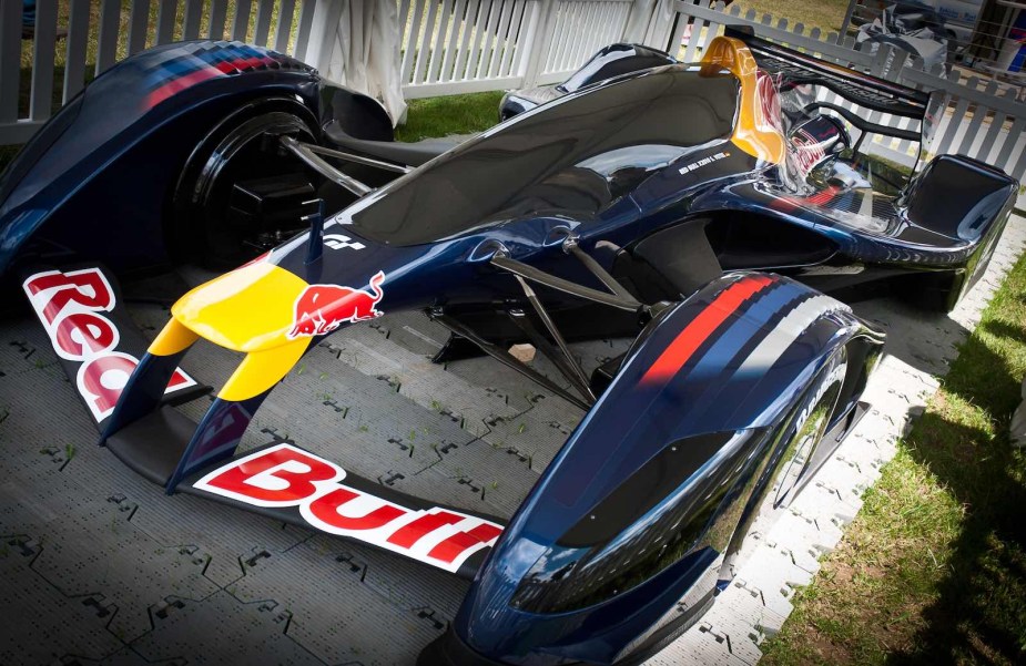 Experimental race car parked in a fence and covered with Red Bull logos.