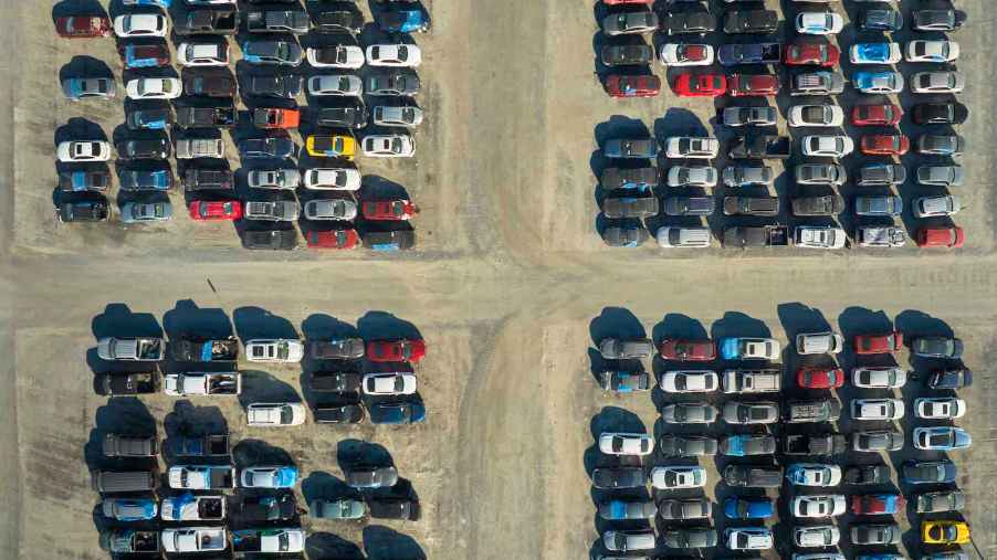 Rows of crossover SUVs and cars parked in a salvage yard.