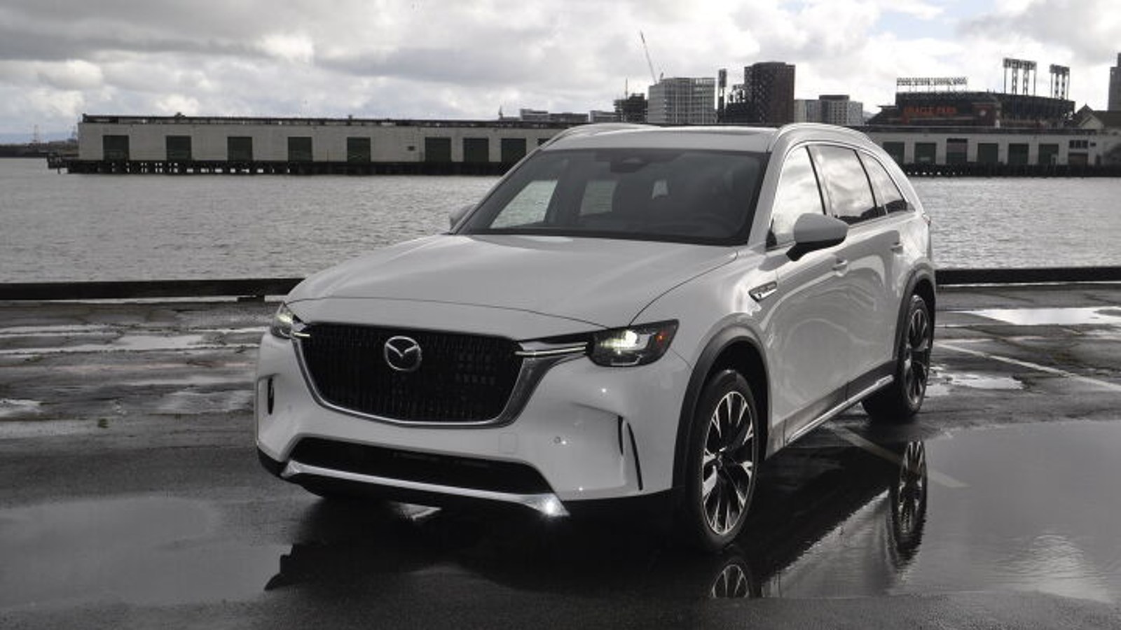 White 2024 Mazda CX-90 parked near a body of water. This midsize SUV is fun to drive.