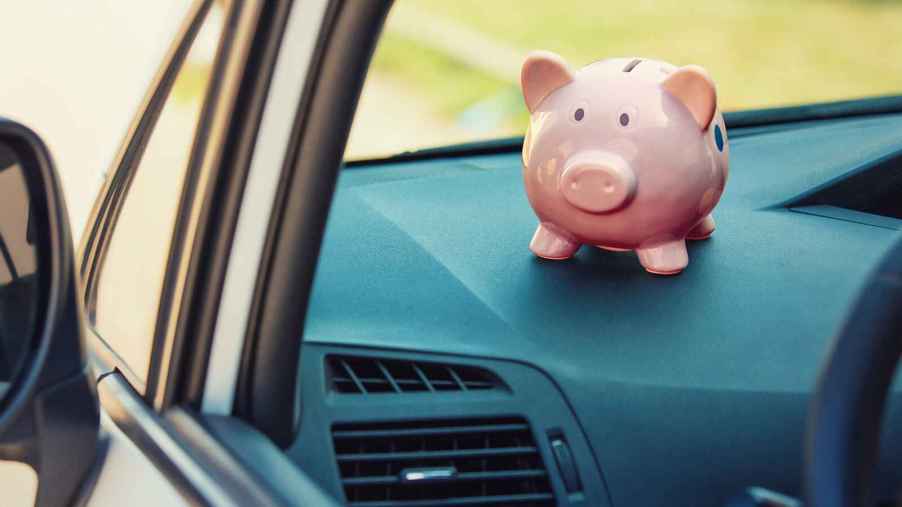 A pink piggy bank sitting on the dash of a car