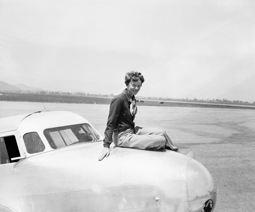 Amelia Earhart poses on the nose of her Lockheed Electra airplane
