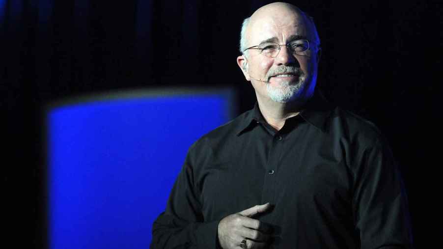 Dave Ramsey speaking at an event in 2011 giving money advice including best way to buy a car wearing a black shirt and blue and black background