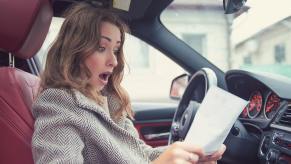 Woman stares at the contract to buy a new SUV with a destination charge.