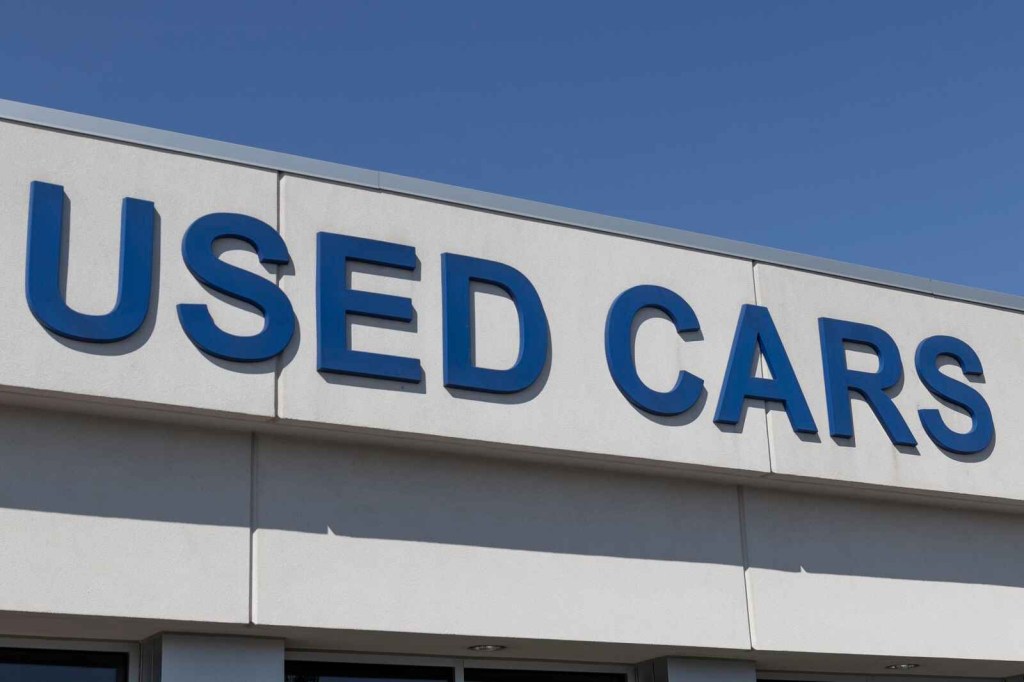 A commercial building sign with "USED CARS" lettering in blue is shown in close proximity