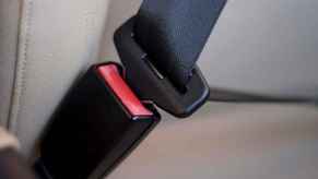 A car's black seat belt is shown buckled into the buckle without a person