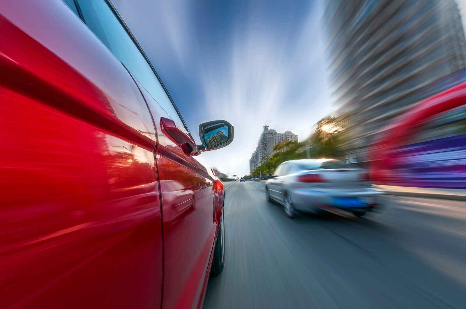 A close view of a red car tailgating a silver car driving fast