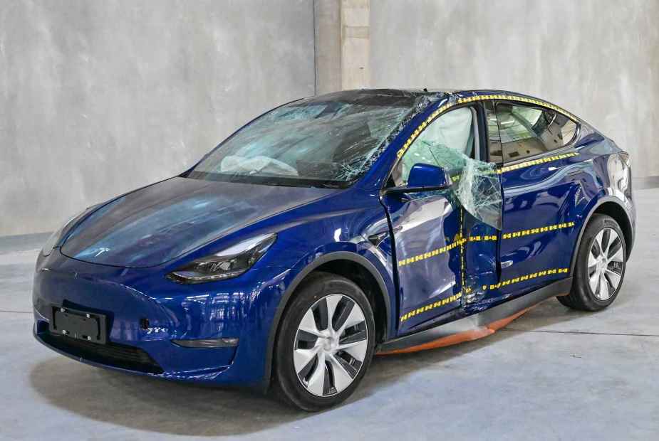 A blue Tesla Model Y EV is crash tested damage to left front door area broken window glass