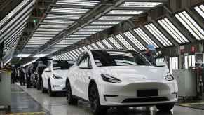 A row of white Tesla cars are shown on the factory floor in Shanghai