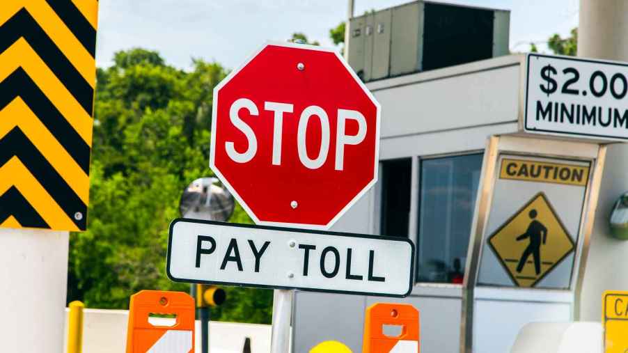 A red stop sign is posted above another sign with the directive "PAY TOLL" on a toll road