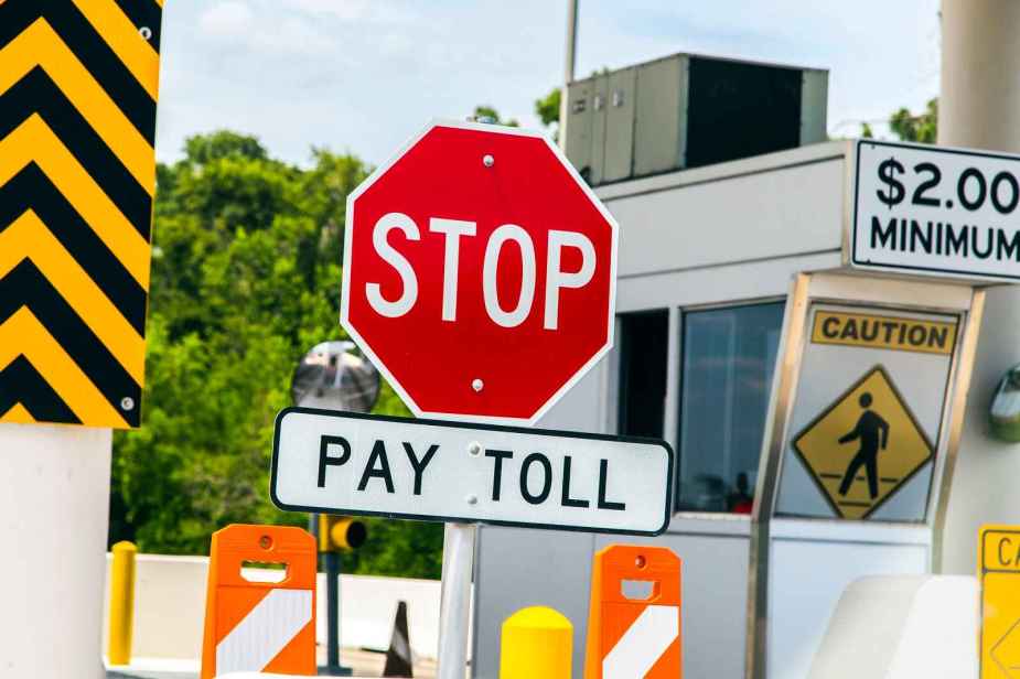 A red stop sign is posted above another sign with the directive "PAY TOLL" on a toll road