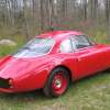 Red 1961 SSZ Stradale prototype parked in front of the woods.