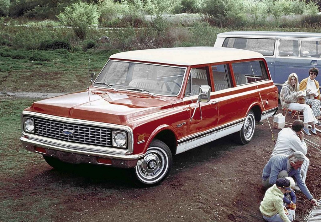 A red 1972 Chevrolet Suburban parked with a line of family people fishing