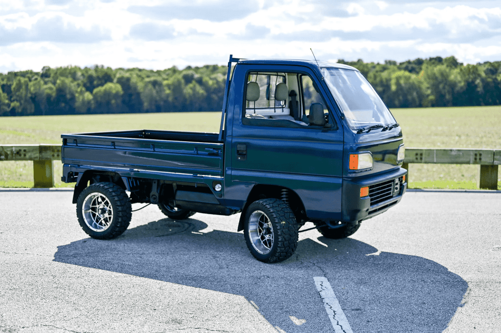 A dark blue metallix 1993 Honda Acty truck parked in right front profile view