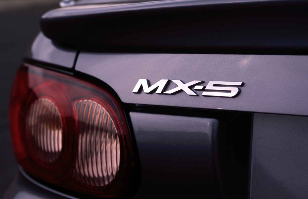 A close up of the left rear Mx-5 badge on a 2004 Mazda MX-5 Miata