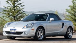 Silver 2005 Toyota MR2 Spyder sports car posed in front of an outdoor scene.