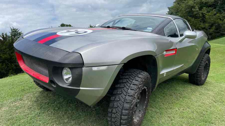 The grille and front headlight of a lifted sports car parked on grass.