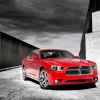 A red 2012 Dodge Charger is parked in right front angle view black and white background