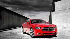 A red 2012 Dodge Charger is parked in right front angle view black and white background