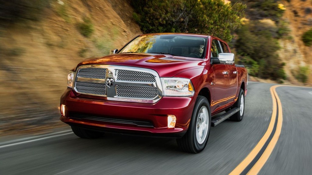 Red 2014 Ram 1500 pickup truck driving down the road.