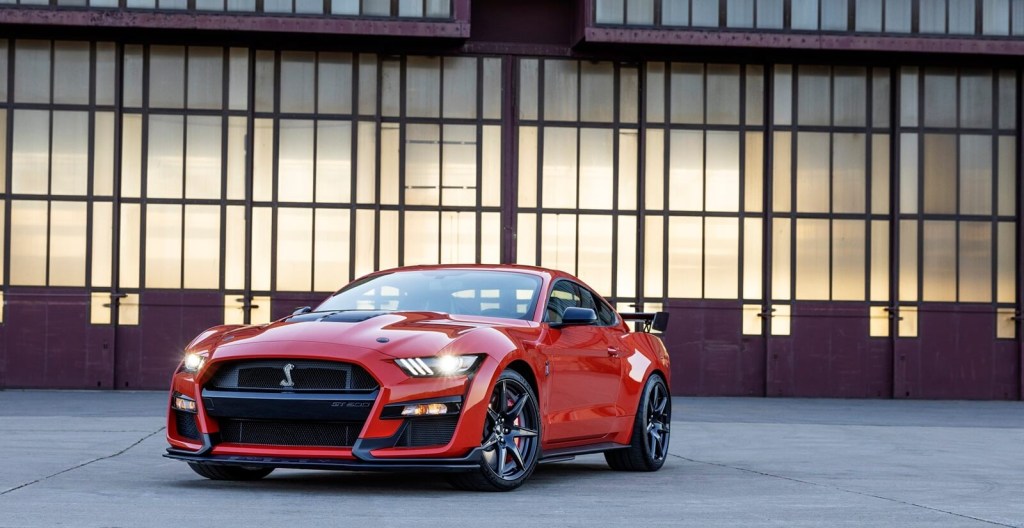 An orange S550 Shelby GT500 parks with its lights on.