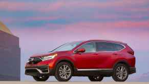 A red 2022 Honda CR-V Hybrid SUV parked with a pink and blue sunset in the background