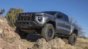 2024 GMC Canyon AT4X AEV midsize off-road truck tackling a rugged outdoor trail.