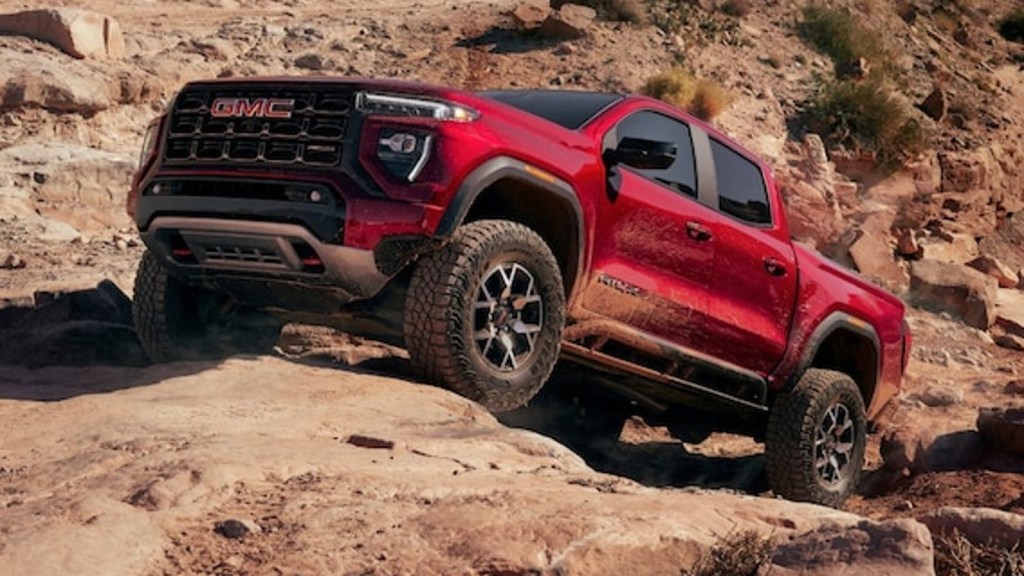 Red 2024 GMC Canyon midsize truck taking on an intense off-road trail.