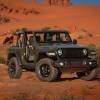 A green 2024 Jeep Wrangler JL Willys model parks without doors or a roof.