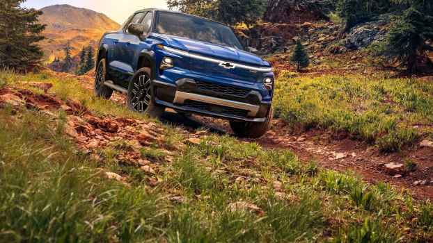A blue 2024 Chevrolet Silverado EB drives down a grass covered dirt hill