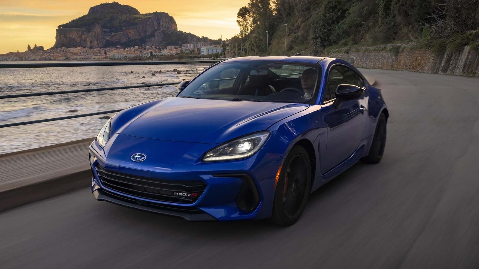 Blue 2024 Subaru BRZ tS sports car driving along the coast.