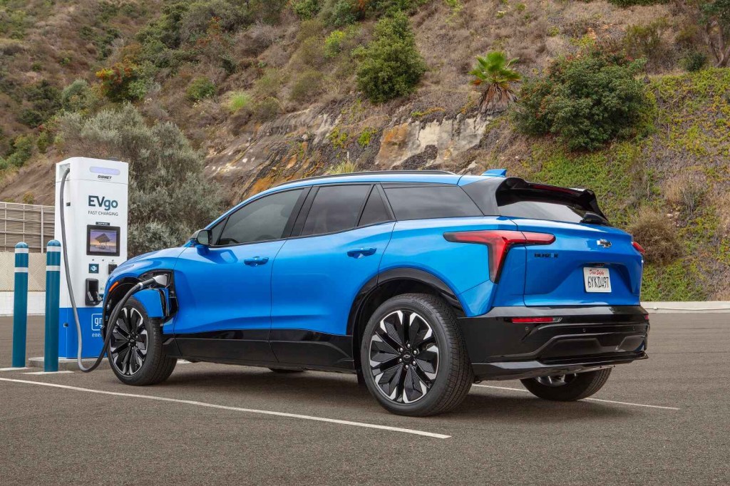 A blue 2024 Chevrolet Blazer EV SUV shown charging at a charge station in left rear profile view GM now offers free EV safety training for first responders