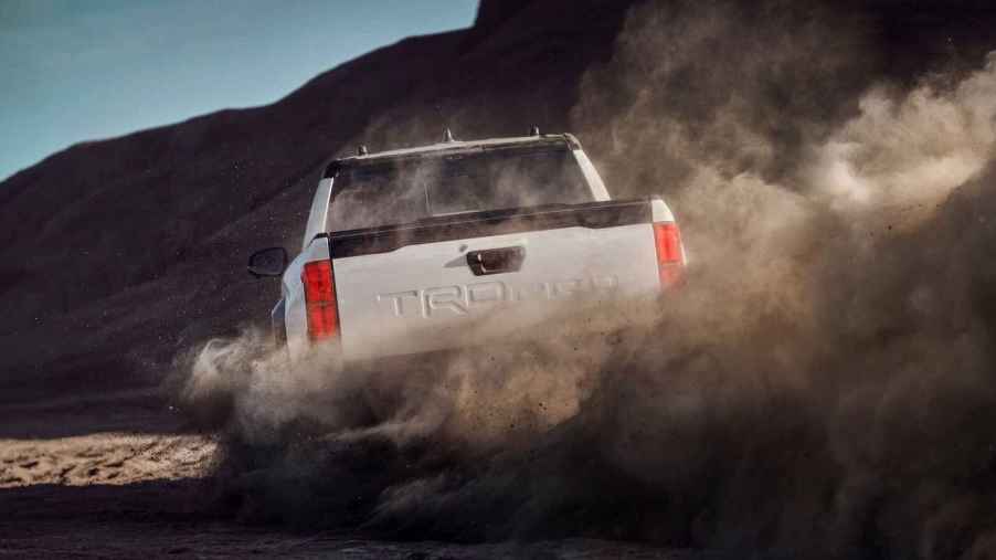 A white 2024 Toyota Tacoma TRD Pro pickup truck shown from behind kicking up dirt
