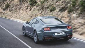A 2024 Ford Mustang GT, the pricier alternative to the EcoBoost, drives down a mountain road.