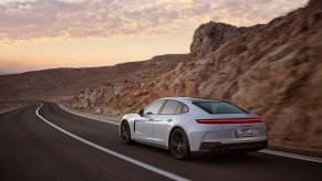 A 2025 Porsche Panamera 4S E-Hybrid shows off its rear-end styling in the desert.