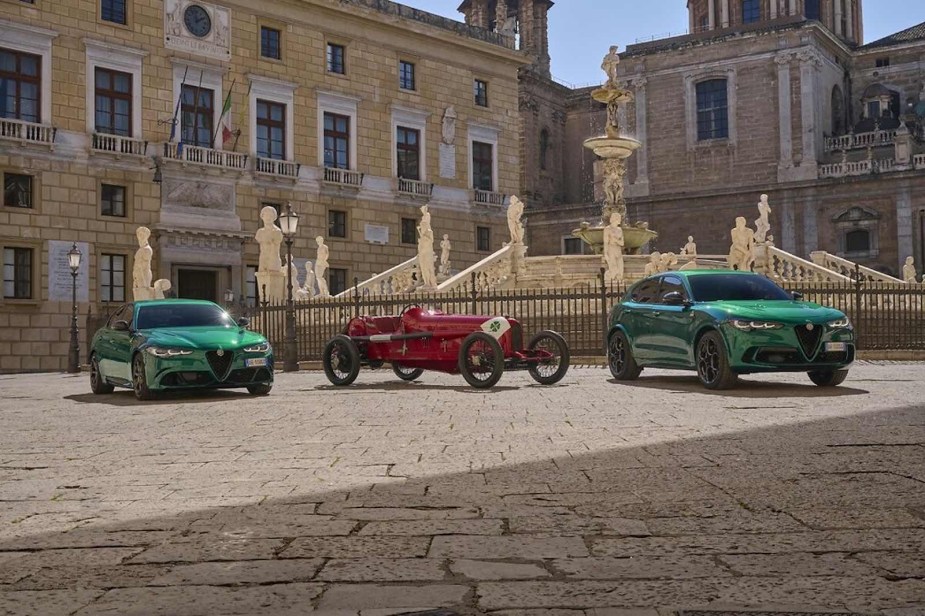 An Alfa Romeo Giulia, Grand Prix roadster, and crossover SUV in a courtyard.