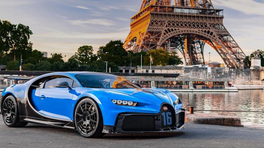 Blue Bugatti Chiron supercar parked in front of the Eiffel Tower.