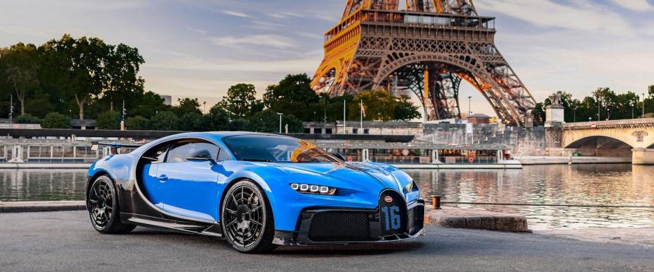 Blue Bugatti Chiron supercar parked in front of the Eiffel Tower.