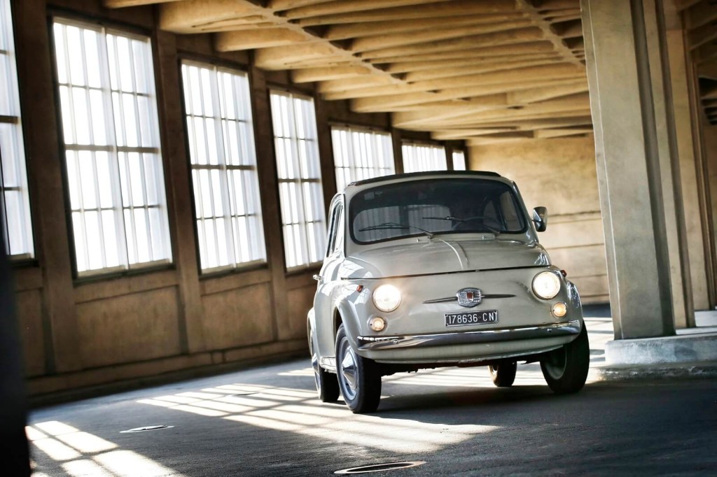 An old, classic FIAT 500 takes a corner in an structure.