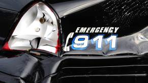 The "Emergency 911" decal on the smashed fender of a crashed police car.