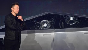Tesla CEO Elon Musk stands next to a Cybertruck with shattered windows.