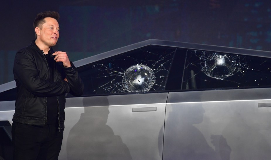 Tesla CEO Elon Musk stands next to a Cybertruck with shattered windows.