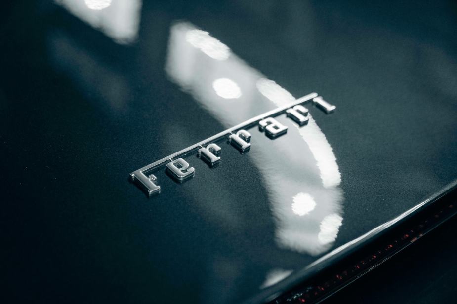A chrome Ferrari logo on the trunk of a gray car.