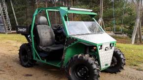 Green UTV side-by-side assembled with old car parts parked in the woods.