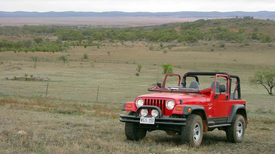 A bright-red Jeep Wrangler TJ with it a folded windshield.