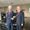 President Joe Biden and a GM exec shake hands while he takes delivery of a Cadillac ATS-V