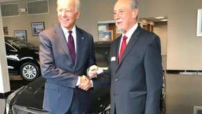 President Joe Biden and a GM exec shake hands while he takes delivery of a Cadillac ATS-V