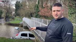 U.K. hero explaining how he used ratchet straps to save a mother and toddler from the sinking car visible in the background.