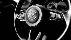 The Mazda logo on the steering wheel of a car.